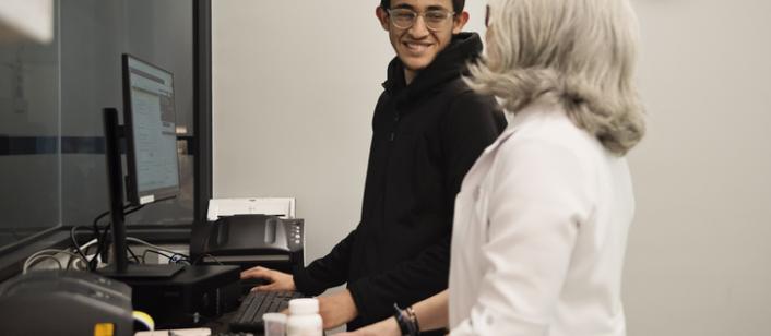 student smilies at a mentor while working at a computer