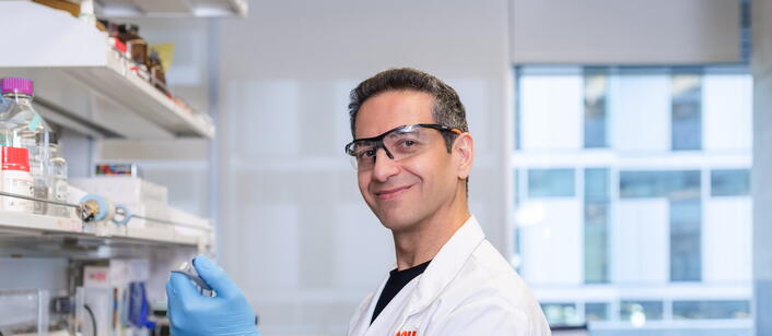 Lab worker smiling at camera while filling a pipette