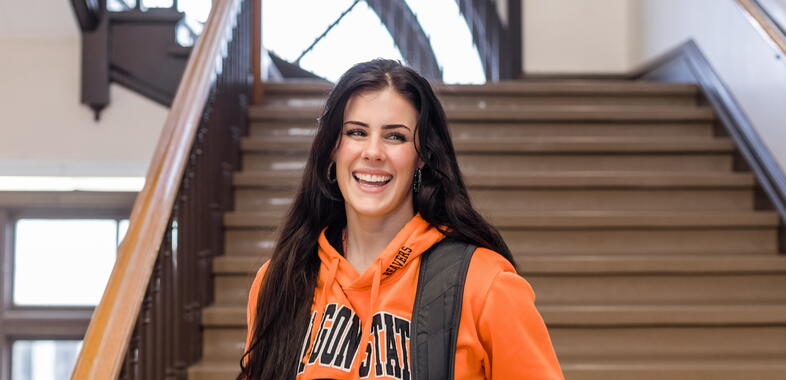 A girl looks at the camera, smiling, wearing beaver gear in the college of pharmacy