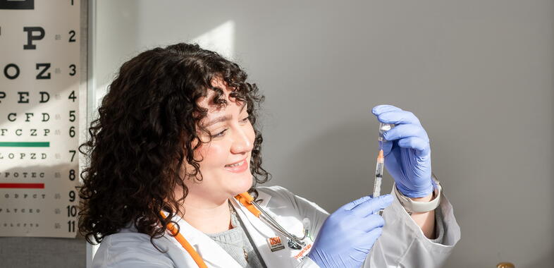 A pharmacist pulls syrum from a bottle using a vaccine