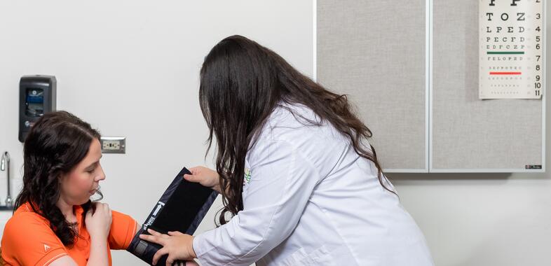 A pharmacists places a blood pressure monitor on someone's arm