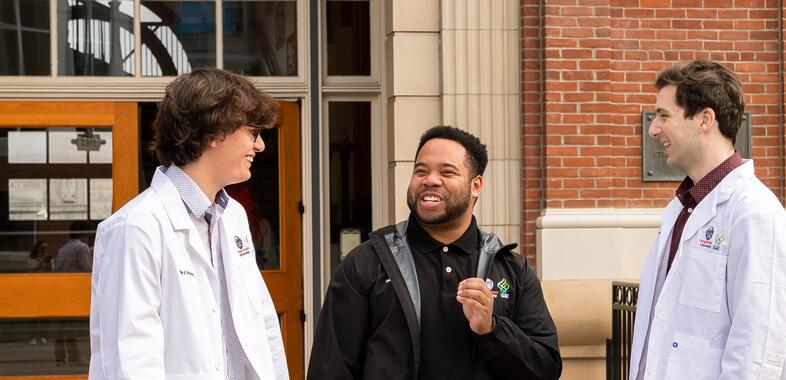 Three students talk outside of the college of pharmacy